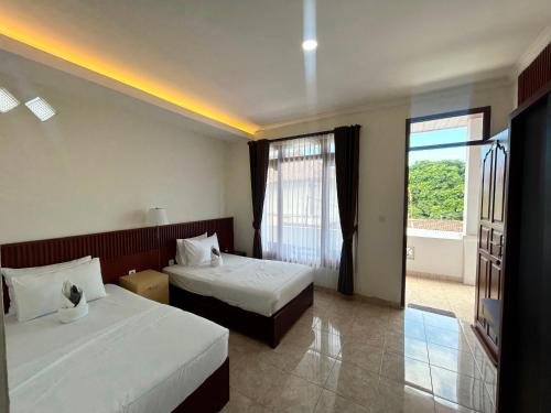 a hotel room with two beds and a window at Pantai Ayu Homestay in Padangbai