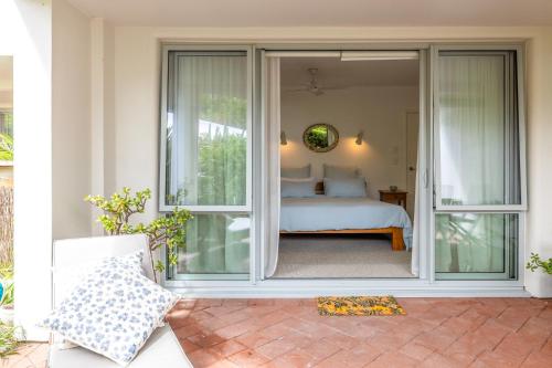 a bedroom with sliding glass doors on a patio at Beachfront 25 The Strand Moana in Waiheke Island