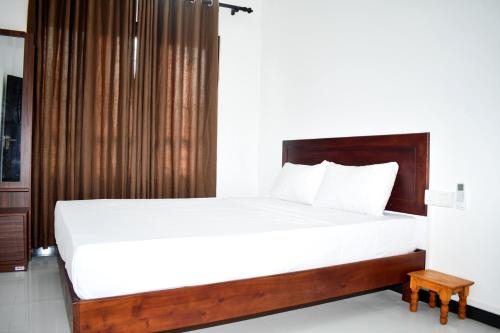 a bedroom with a large bed with white sheets at Lasya Residence in Trincomalee
