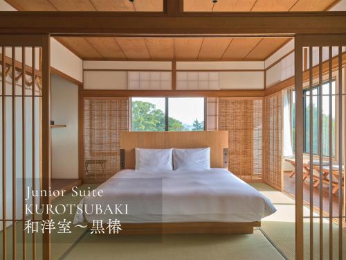 ein Schlafzimmer mit einem Bett und einem großen Fenster in der Unterkunft Ohana in Yanagawa