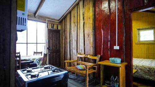 a kitchen with a stove and a chair in a room at Refugio de montaña Küme Mongüen in Malalcahuello