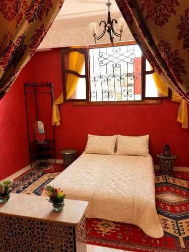 a bedroom with a bed and a red wall at Tafoukt 2 in Kasba Aït Youdi