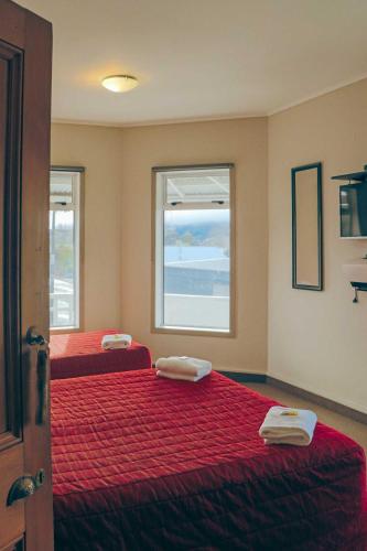 a bedroom with two beds with red sheets and a window at Hampden Hotel Murchison in Murchison
