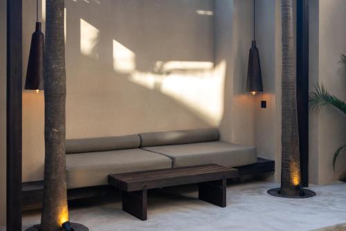 a couch and a bench in a room with two palm trees at The Sirocco Villas Bingin by Sandara in Bingin Beach