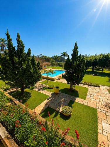 a garden with a swimming pool and trees and grass at Pousada Sítio das Cerejeiras in São Roque