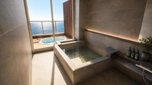 a bathroom with a jacuzzi tub and a window at AMANE resort SEIKAI in Beppu