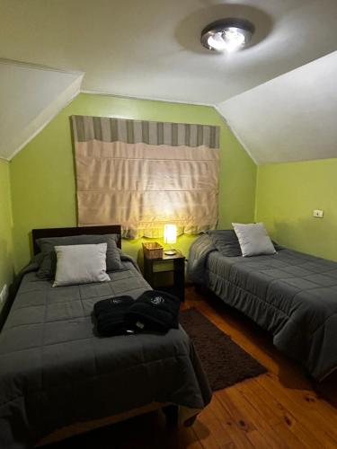 two beds in a room with green walls at Hostal el valle in Angol