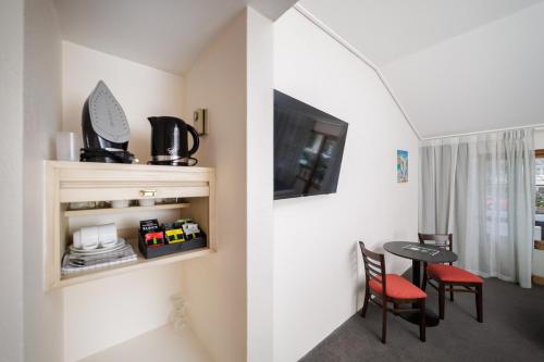 a small dining room with a table and a tv at Carnmore Hotel Lower Hutt in Lower Hutt