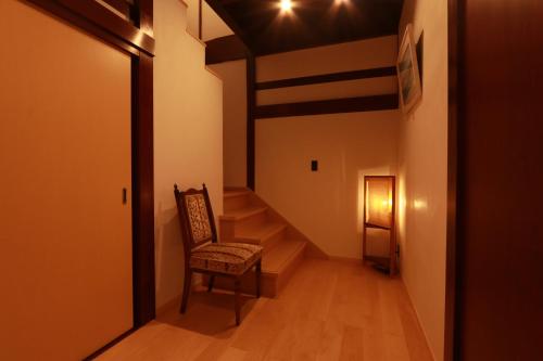 a hallway with a chair and stairs in a house at 龍助25ANNEX Ryusuke25ANNEX in Komatsu
