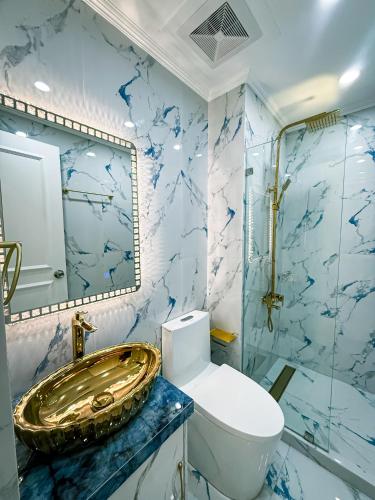 a bathroom with a gold sink and a toilet at City View at The Gramercy Residences in Makati