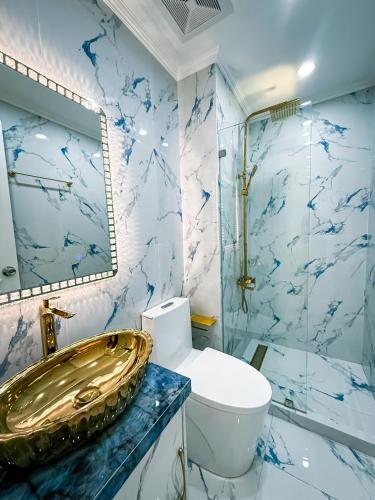 a bathroom with a gold sink and a toilet at City View at The Gramercy Residences in Makati