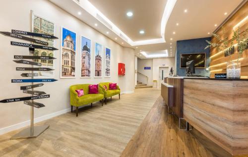 a lobby with yellow chairs and a television in a building at Hotel Madrid Centro, Affiliated by Meliá in Madrid