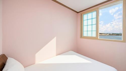 a bedroom with a bed and a window at Geoje Youngsu Pension in Geoje