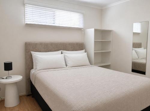 a white bedroom with a bed and a window at Badgee Park in Sussex Inlet