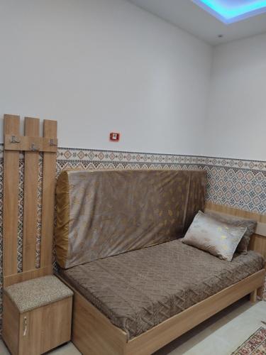 a wooden bed with a pillow on top of it at شقق يوسف للكراء in Gabès