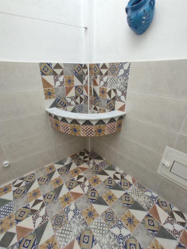 a bathroom with a toilet with tiles on the floor at شقق يوسف للكراء in Gabès