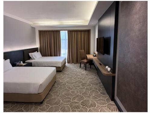 a hotel room with two beds and a flat screen tv at Grand Riverview Hotel in Kota Bharu