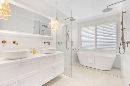 a white bathroom with two sinks and a shower at Whitepepper Cottage in Pokolbin