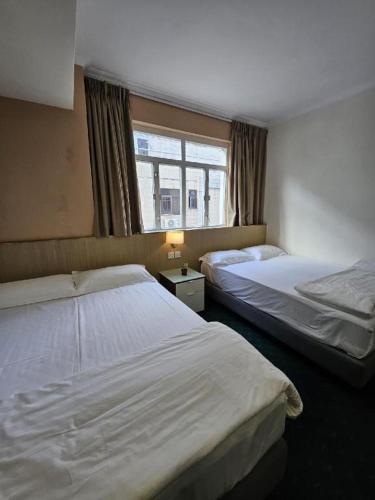 a hotel room with two beds and a window at Man Va Hotel in Macau