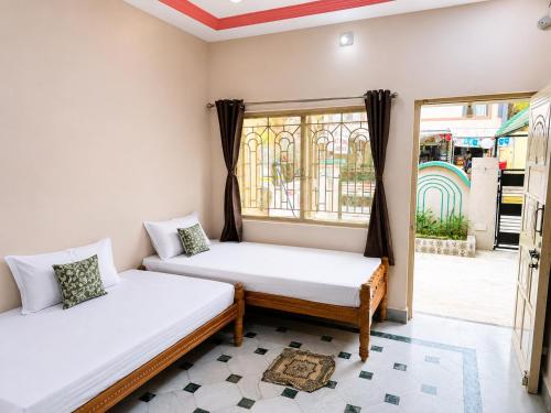 two beds in a room with a window at Evergreen Bungalows in Dwarka