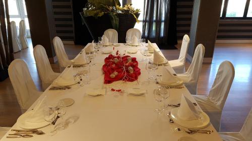 una larga mesa blanca con sillas blancas y un centro de mesa de flores en Hotel Aguadoce - Louzao, en Viveiro