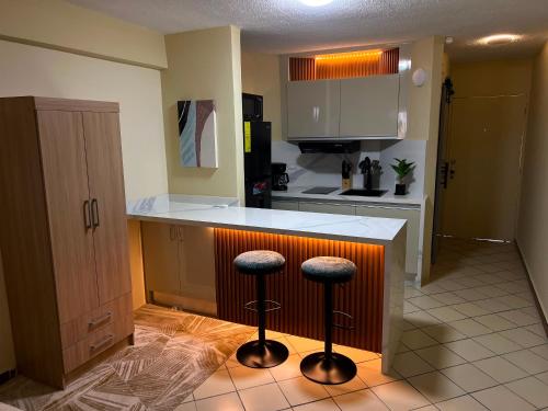 a kitchen with a counter and two bar stools at Exclusiva suite en Hotel Marbellamar in Pampatar