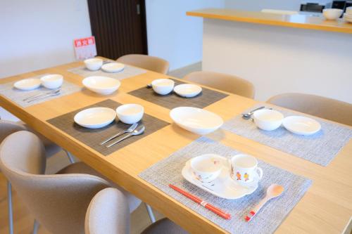 a wooden table with white bowls and cups on it at Villa UMMINA in Tahara