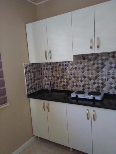 a kitchen with white cabinets and a sink at Send Apart Otel in Antalya