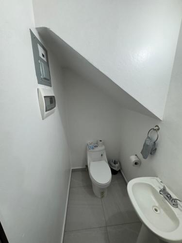 a white bathroom with a toilet and a sink at TadeoHouse in Tijuana