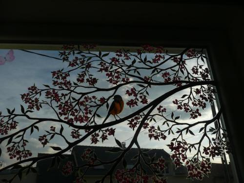 a bird sitting on a tree branch in a window at Roulotte la Dominique in Romery