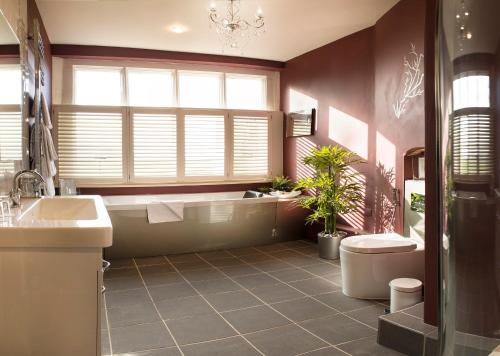 a bathroom with a tub and a toilet and a sink at Hatherley Manor Hotel & Spa in Gloucester