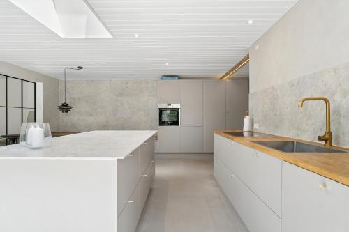 a kitchen with white cabinets and a sink at Luxury Retreat Surrounded By Nature in Rønde