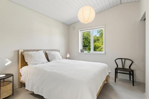 a white bedroom with a large bed and a window at Luxury Retreat Surrounded By Nature in Rønde