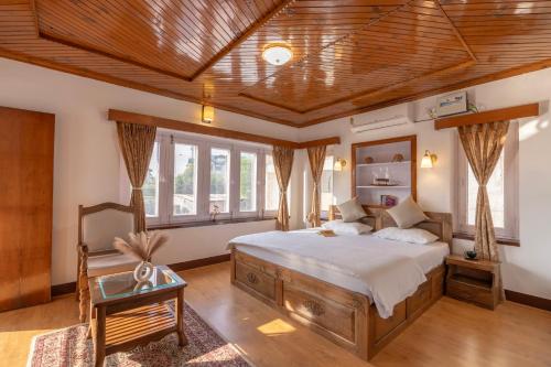 a bedroom with a large bed and a wooden ceiling at Blume House- 4BHK Holiday Home with Kitchen & Garden in Srinagar