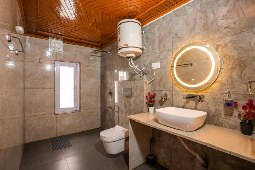 a bathroom with a sink and a toilet and a mirror at Blume House- 4BHK Holiday Home with Kitchen & Garden in Srinagar