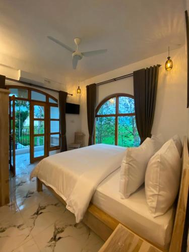 a bedroom with a large white bed with a window at Tetebatu Sunset House in Tetebatu
