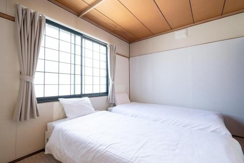 two beds in a room with a window at c Furano A in Furano