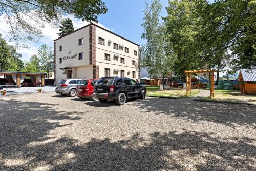 a parking lot with cars parked in front of a building at Комплекс СільДар in Solotvyno