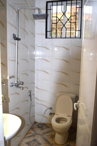a bathroom with a toilet and a sink and a window at Nyerere Green Lodge in Kwangwazi