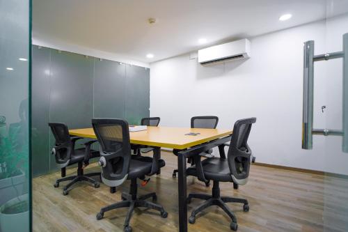 a conference room with a wooden table and black chairs at Saltstayz Express - Golf Course Road & DLF Phase-1 in Gurgaon