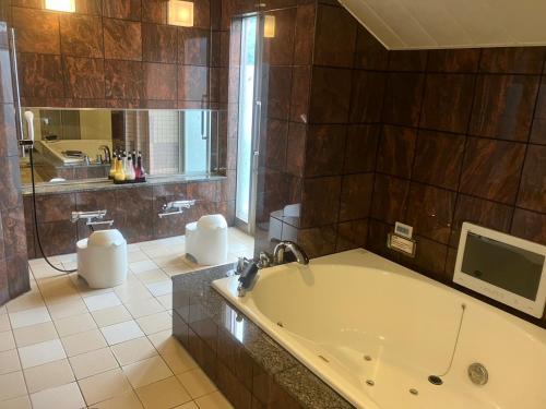 a large bathroom with a tub and a tv at Hulamoon in Maizuru