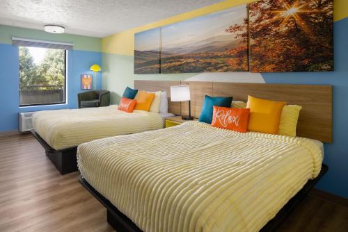 a hotel room with two beds and a painting on the wall at Days Inn By Wyndham Pigeon Forge South in Pigeon Forge
