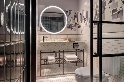 a bathroom with a sink and a toilet and a mirror at Caption by Hyatt Zhongshan Park Shanghai in Shanghai