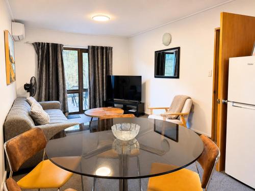 a living room with a table and a refrigerator at Amity Serviced Apartments in Queenstown