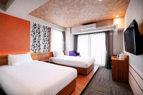 ein Hotelzimmer mit zwei Betten und einem Flachbildfernseher in der Unterkunft Five Hotel Osaka in Osaka