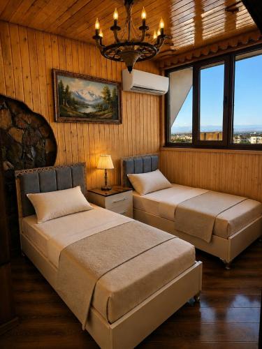 two beds in a room with windows and a chandelier at Ganja Comfort Home in Ganja