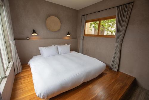 a large white bed in a room with a window at KAYATSUMA OKINAWA Hotel&Resort in Nakijin