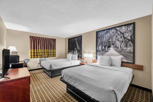 a hotel room with two beds and a television at Super 8 by Wyndham Warner Robins in Warner Robins