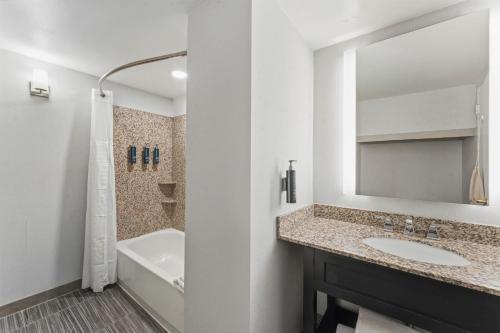 a bathroom with a sink and a tub and a mirror at DoubleTree by Hilton Hotel Wilmington in Wilmington