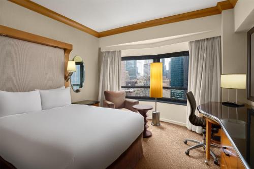 a hotel room with a bed and a desk and a window at New York Hilton Midtown in New York